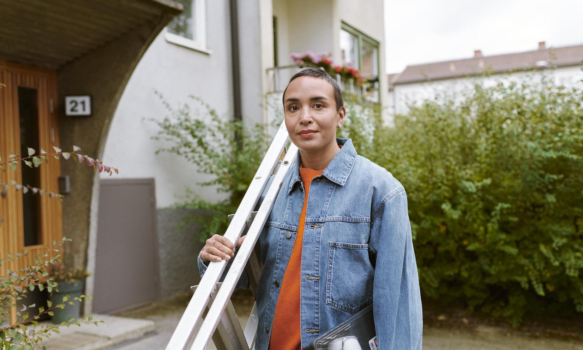 Woman holding a ladder outside her apartment 